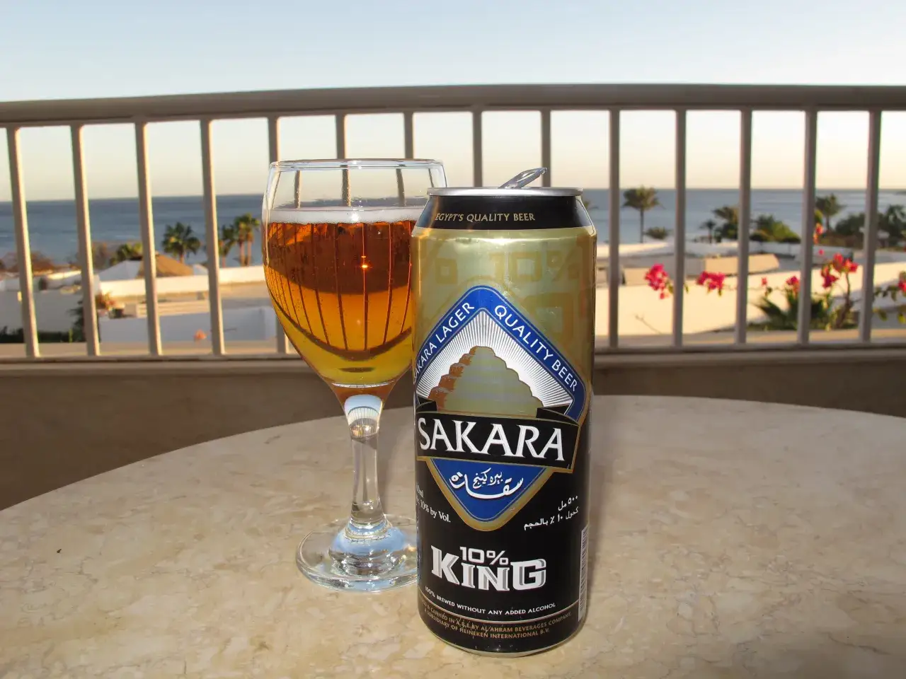 Piwo w Egipcie: puszka i kieliszek Sakara Lager na balkonie z widokiem na morze i palmy. Idealne na upalny dzień.