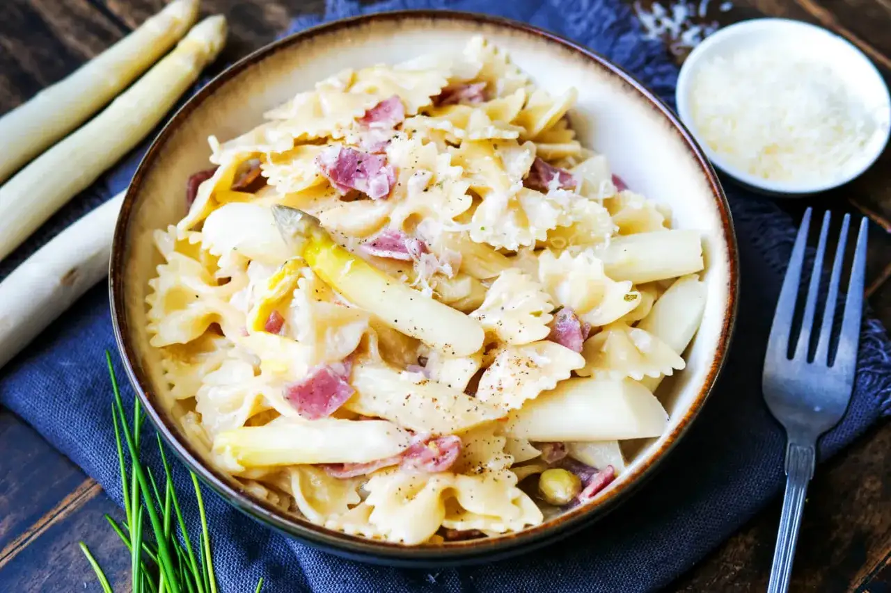 Schmackhafte Spargel Pasta mit Schinken in einer cremigen Sauce, garniert mit frisch geriebenem Parmesan.