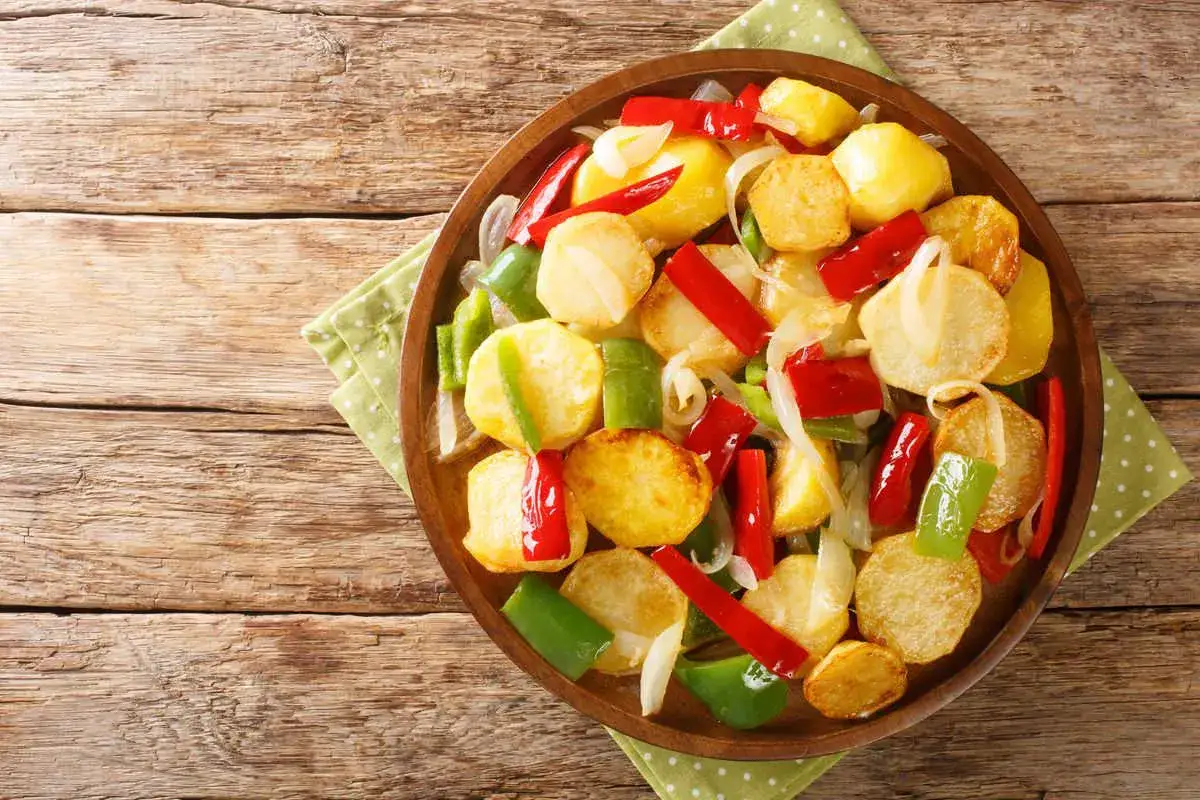 Piatto rustico di patate e peperoni al forno, un contorno colorato e saporito, pronto per essere gustato.