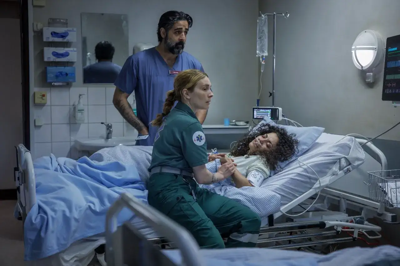 En ambulanssjukvårdare och läkare vakar över en patient på sjukhus.