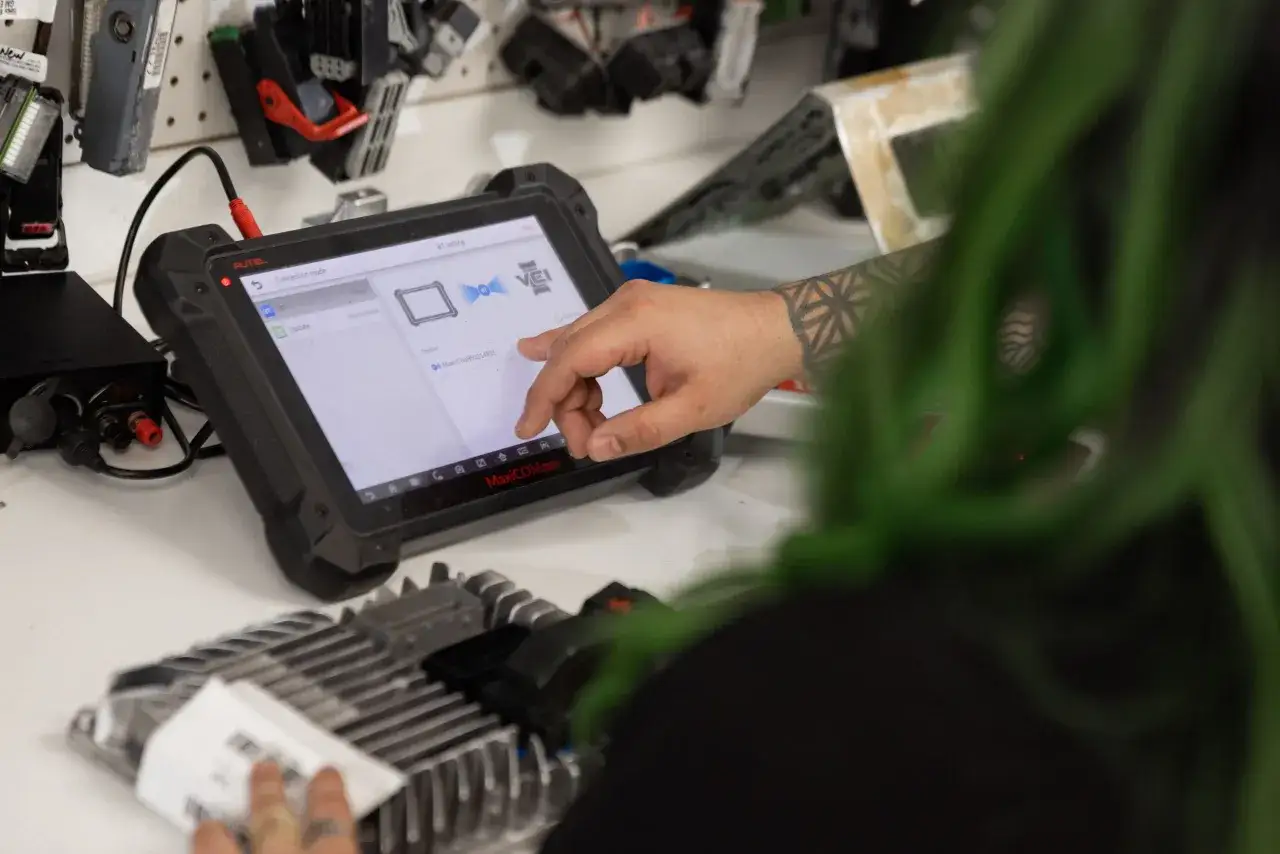 A technician uses a diagnostic tablet to connect to a car's ECM.