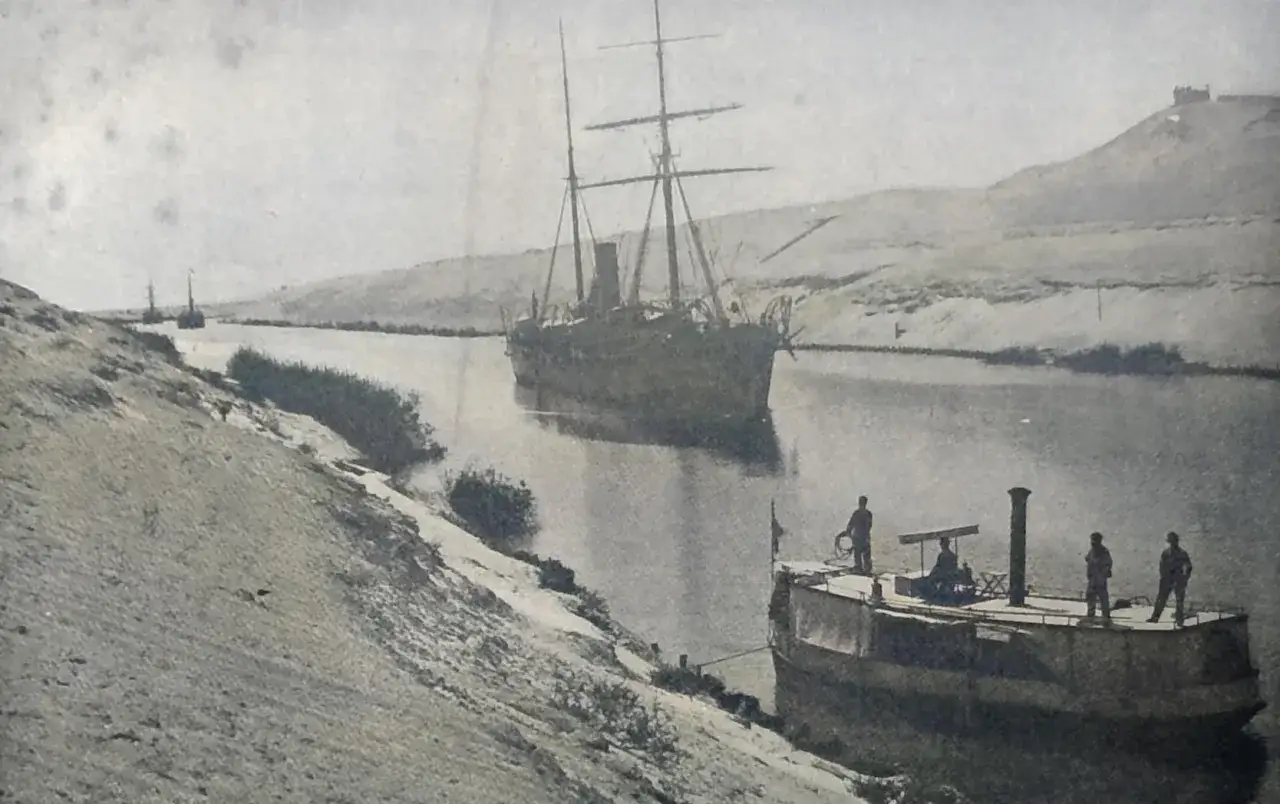Segelschiff und Dampfer im Suezkanal w&auml;hrend des Baus. Arbeiter auf einem kleinen Boot.