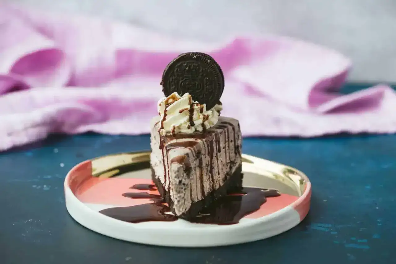 En bit kr&auml;mig oreo cheesecake med choklads&aring;s och vispgr&auml;dde, toppad med en hel Oreo-kaka.