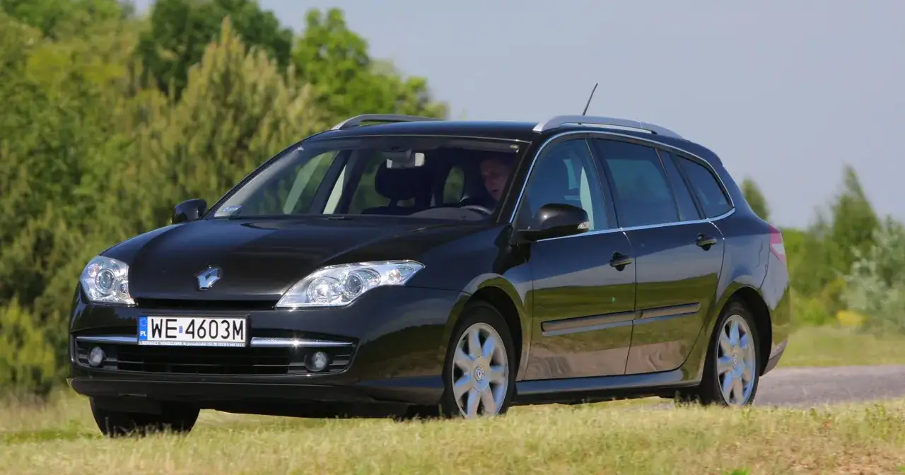 Czarna Laguna 3 2.0 benzyna w wersji kombi jedzie po drodze wśród zieleni.
