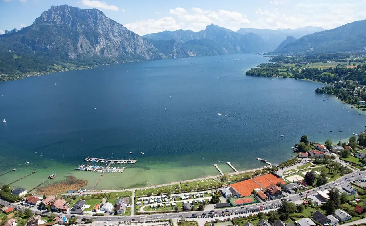 Idyllischer **Camping Traunsee** mit Blick auf den See, Berge und Segelboote. Tennisplätze und ein Yachthafen laden zum Verweilen ein.