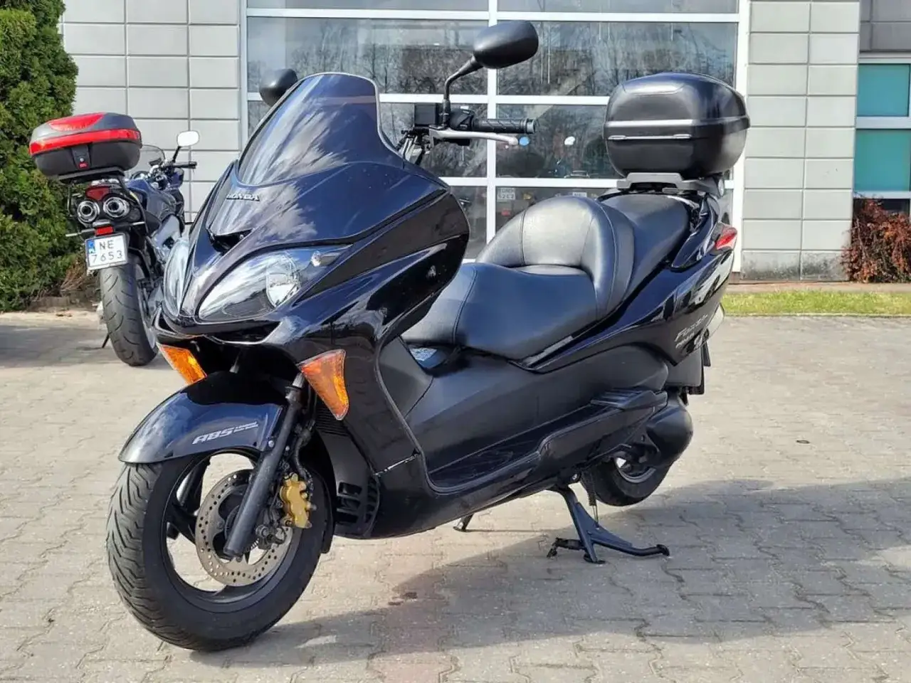 Czarny skuter Honda Forza 250 z kufrem na bagaż, gotowy na miejskie wyprawy.