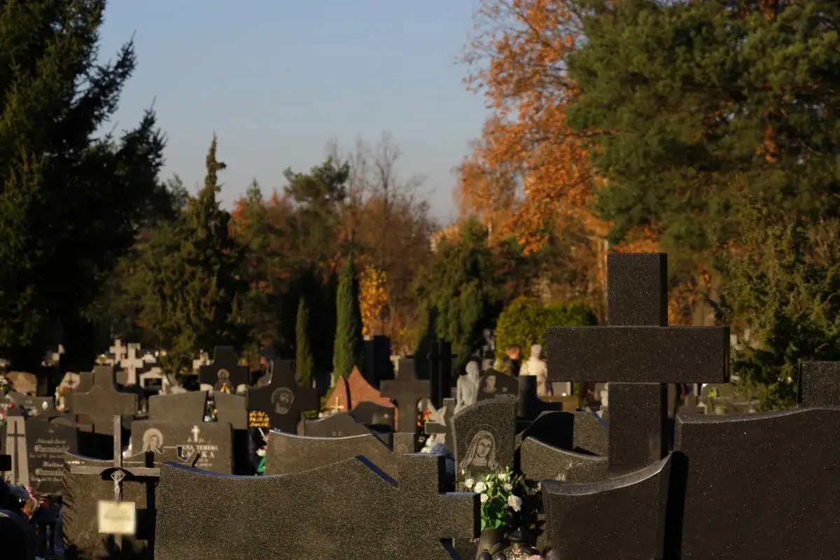 Cmentarz jesienią, krzyże i nagrobki. Wizyta na cmentarzu może wywołać objawy smutku i żałoby, ale jest też miejscem refleksji i radzenia sobie z emocjami.