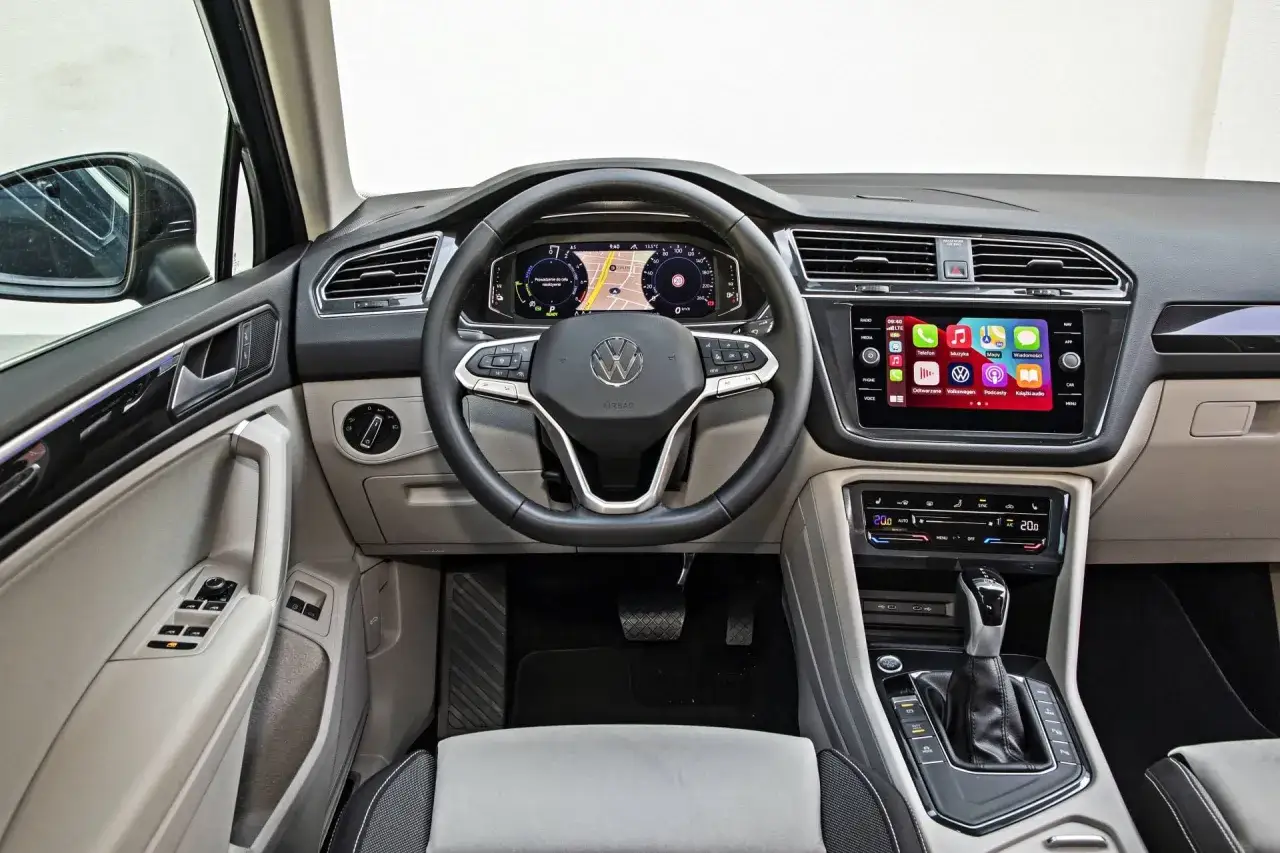 Wnętrze nowego Tiguan z cyfrowymi zegarami, ekranem dotykowym z nawigacją i aplikacjami, kierownicą wielofunkcyjną i automatyczną skrzynią biegów.
