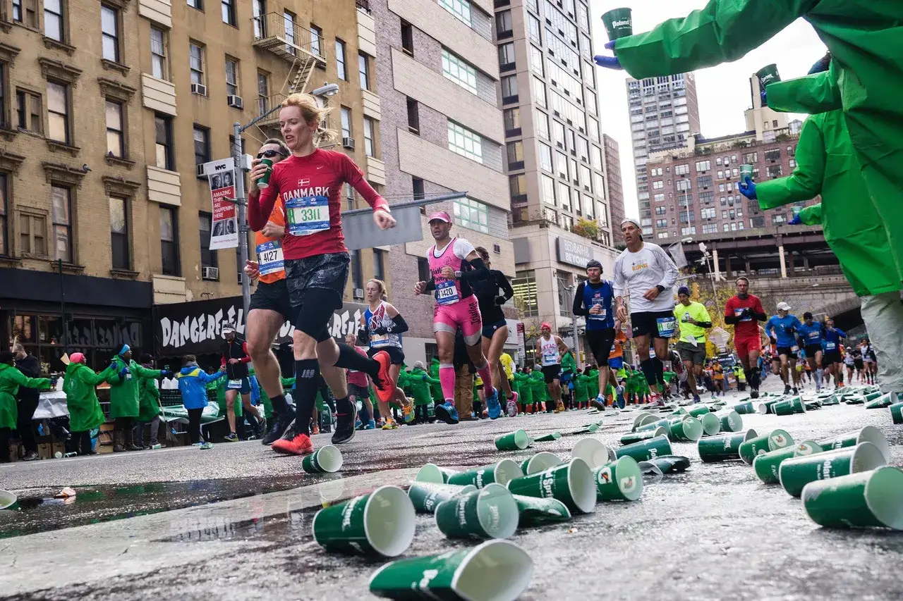 Course à pied 10 km : des coureurs se ravitaillent en eau, des gobelets jonchent le sol.