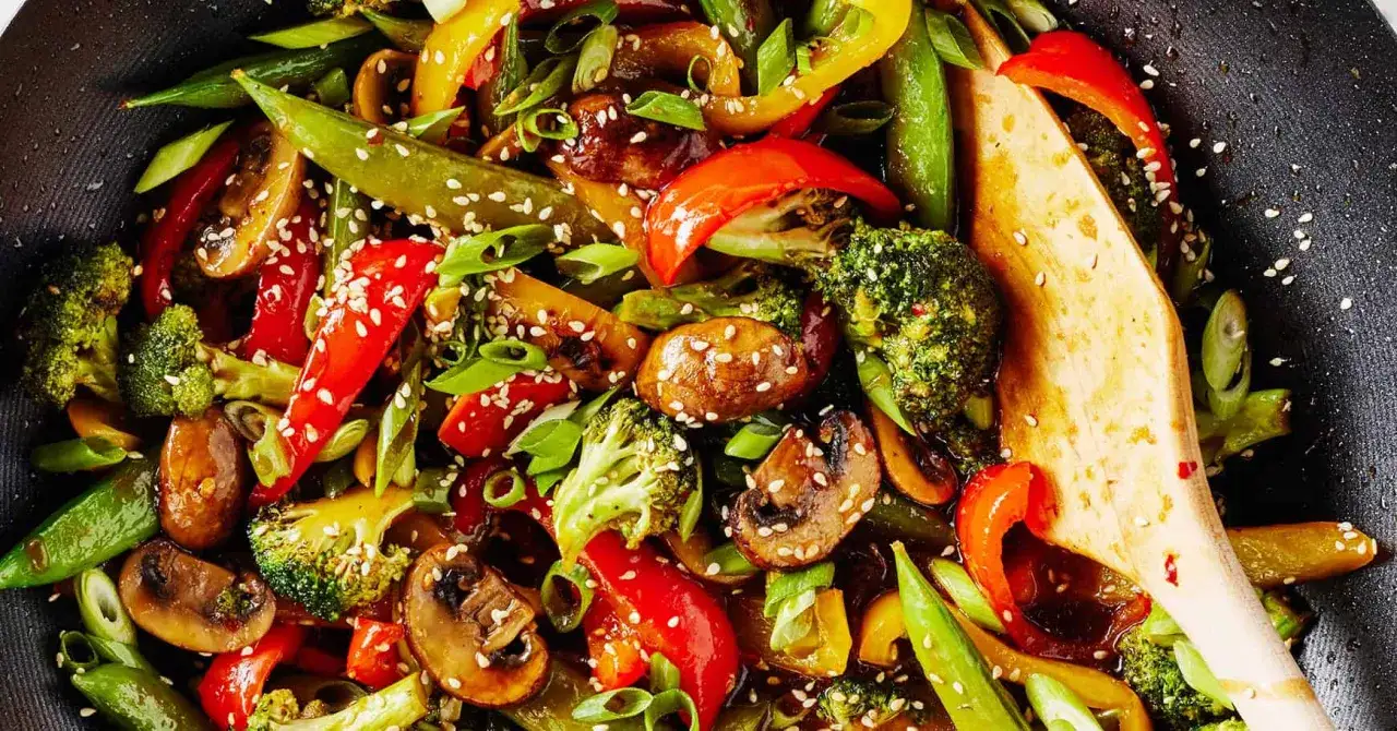 Kolorowy stir fry z brokułami, papryką, pieczarkami i groszkiem cukrowym, posypany sezamem.