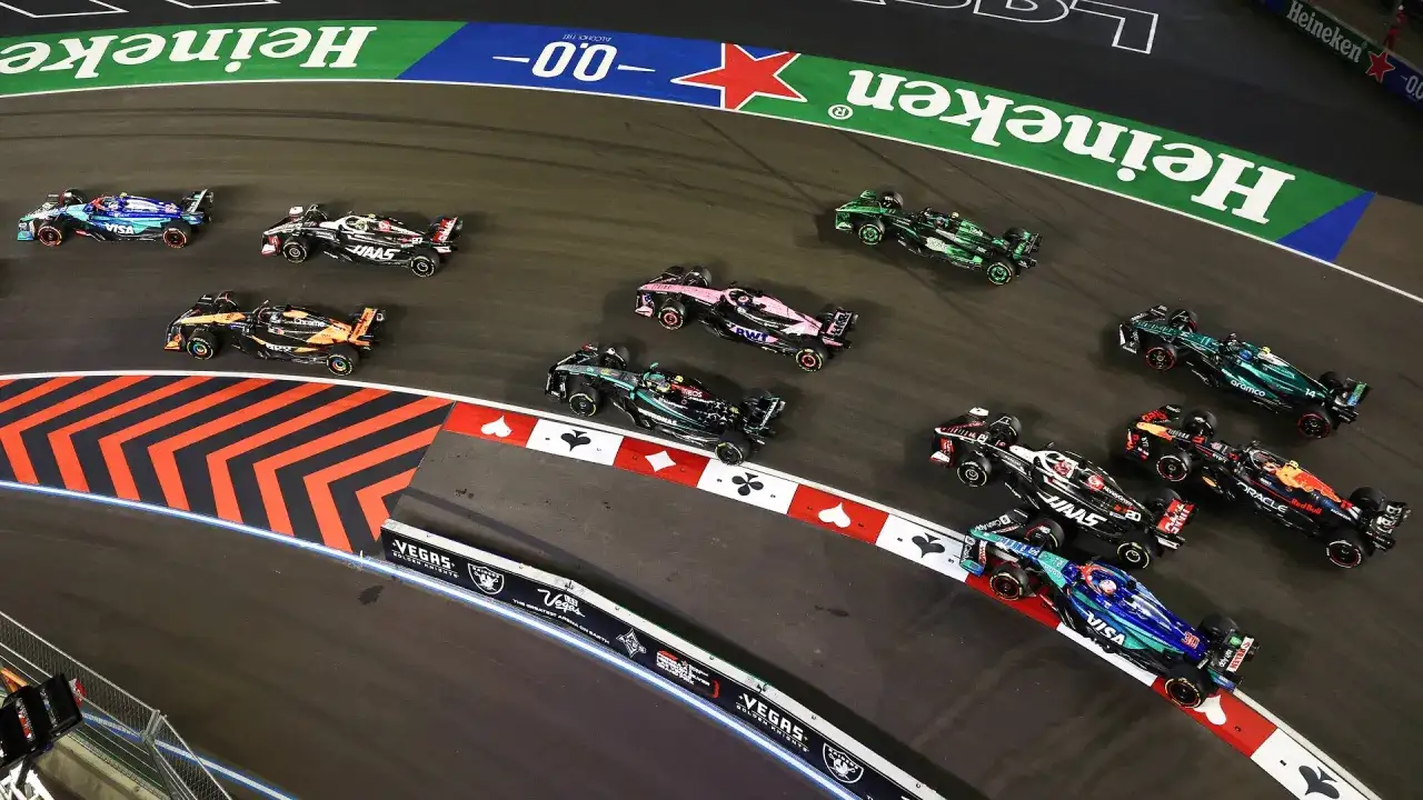 Coches de F1 compiten en la pista durante la qualy F1. Varios monoplazas, incluyendo un McLaren naranja y un Mercedes negro, luchan por la posición.