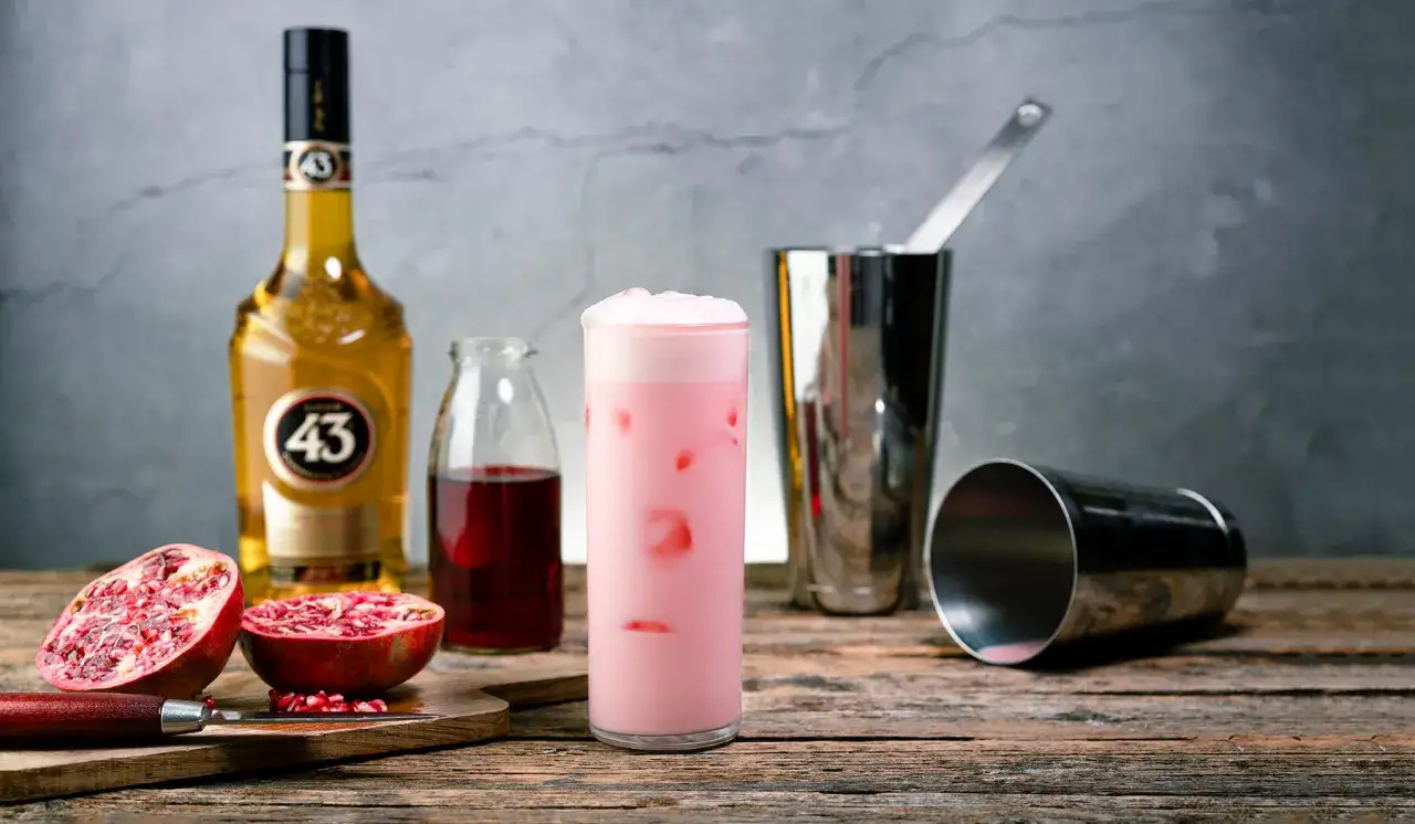 En rosa pantern drink med likör 43, granatäpple och en shaker.