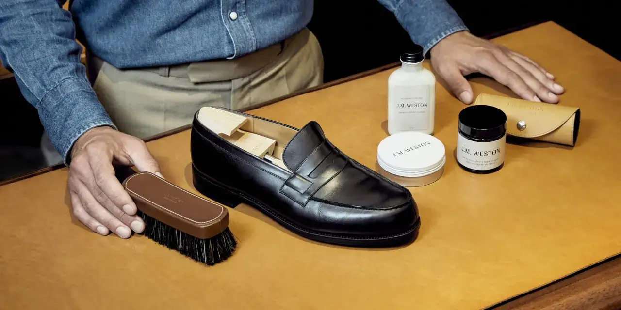 Un homme prépare ses chaussures J.M. Weston pour nourrir le cuir avec des produits de soin.