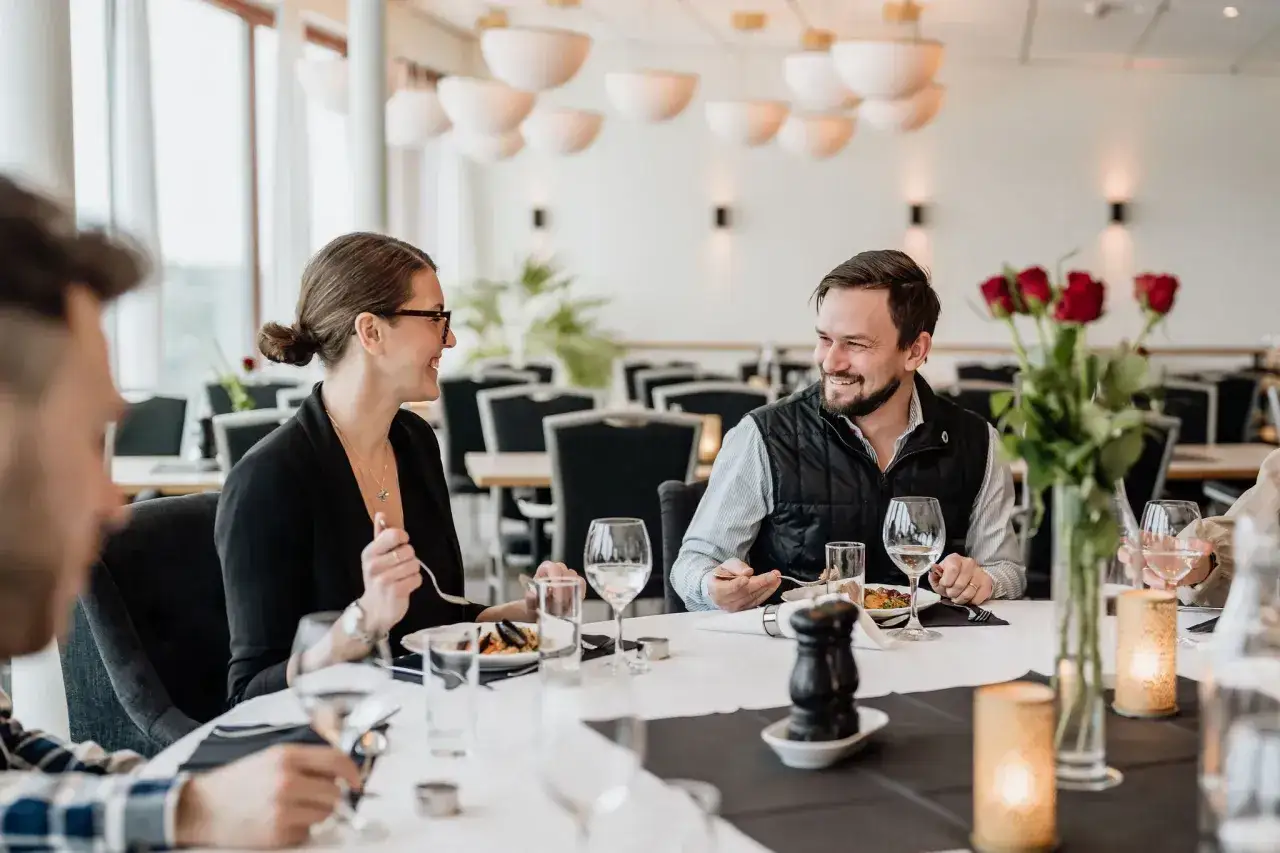 Ett par ler mot varandra vid ett bord på Bohusgården restaurang. Röda rosor och levande ljus skapar en romantisk stämning.