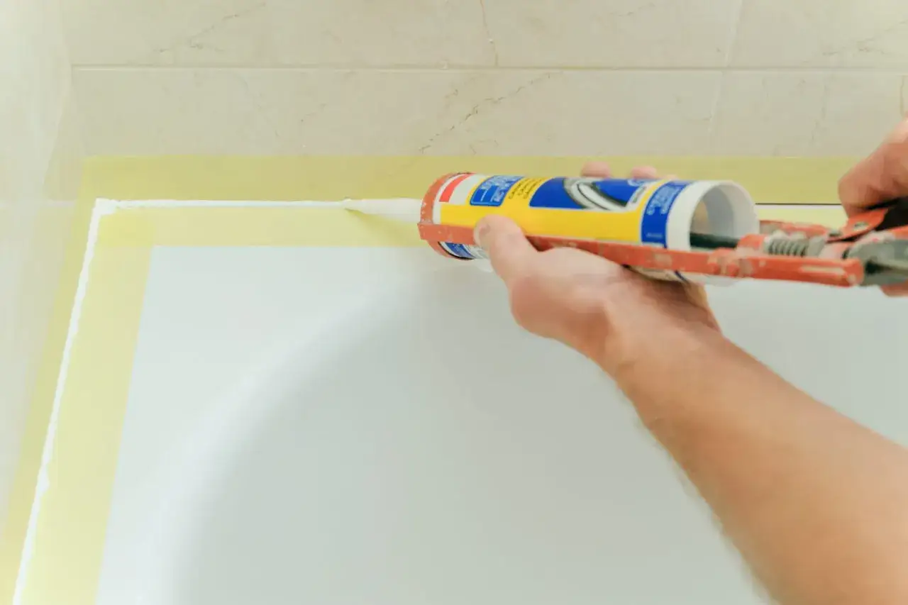 Application de silicone autour d'une baignoire. Le temps de s&eacute;chage du joint silicone est crucial pour une finition parfaite.