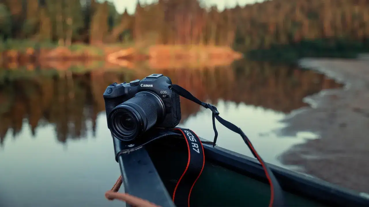 Canon EOS R7 redo i en kanot vid en spegelblank sj&ouml;, redo att f&aring;nga h&ouml;stens f&auml;rger.