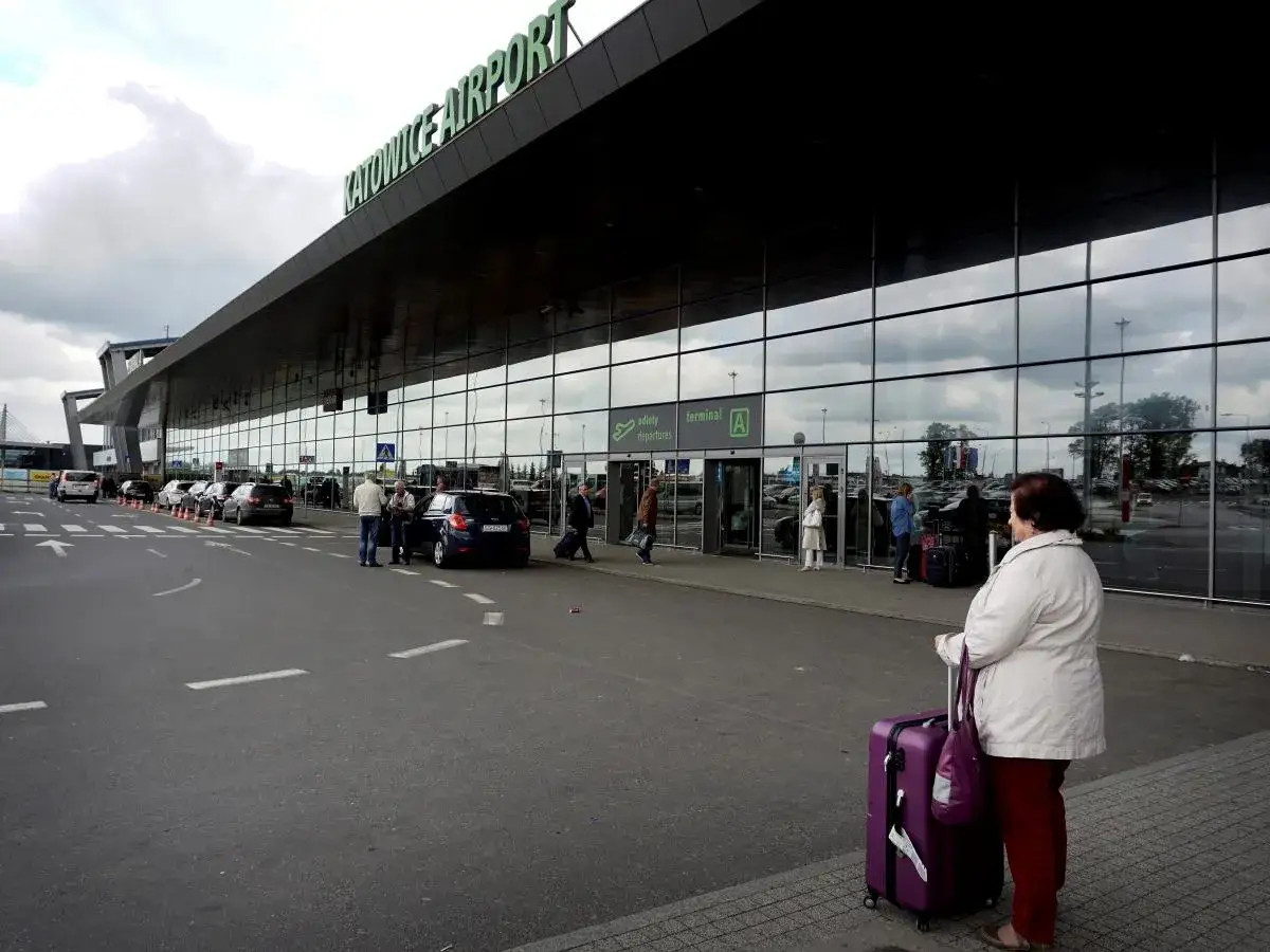 Kobieta z fioletową walizką czeka na lot do Dortmundu z lotniska Katowice.