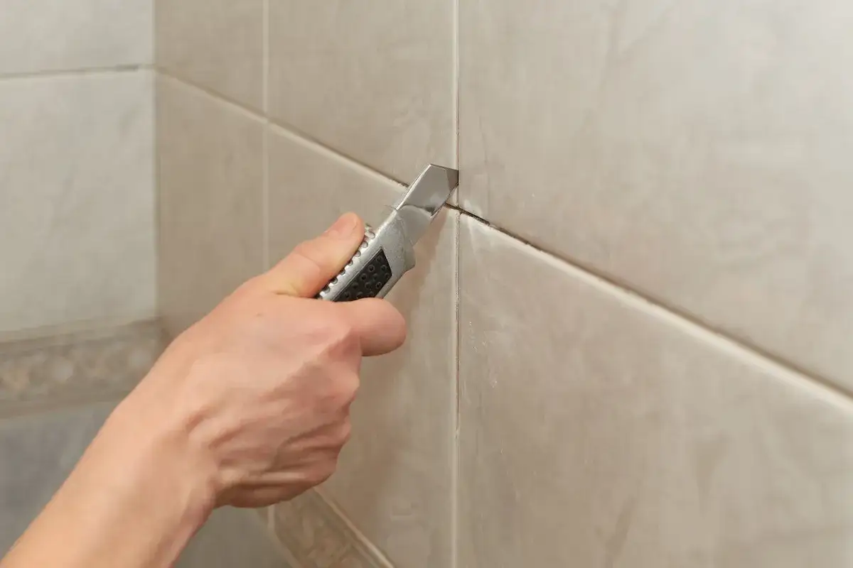 Mano con c&uacute;ter para quitar juntas de azulejos.