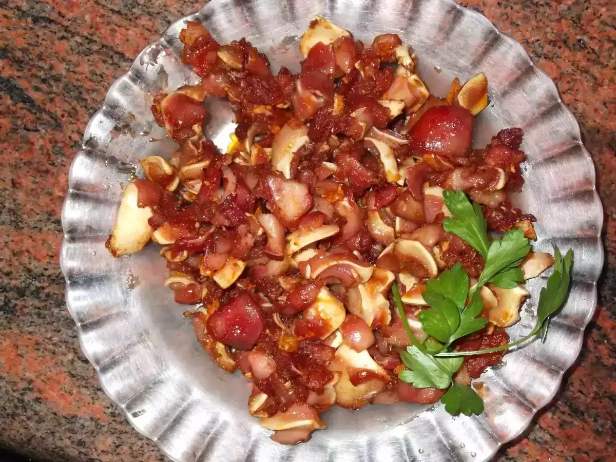 Un plato de oreja de cerdo troceada y cocinada, con trozos crujientes y tiernos, adornado con perejil fresco.