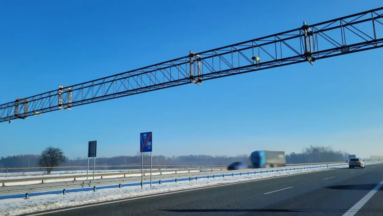 Gantry nad autostradą A4 z systemem odcinkowy pomiar prędkości. W tle samochody i krajobraz zimowy.