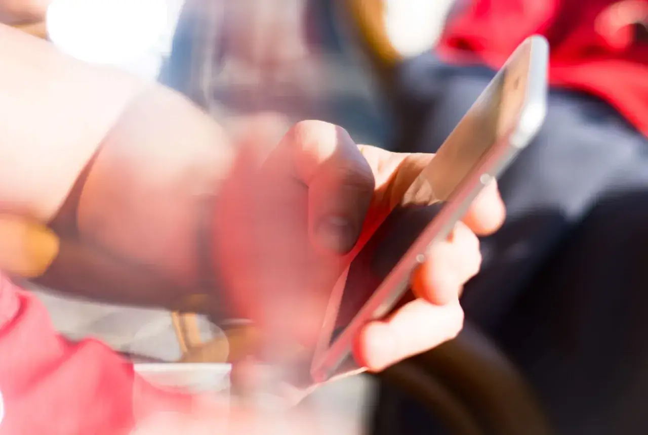 Dłoń trzymająca smartfon, przeglądająca nagł&oacute;wki. Oto clickbait przykłady, kt&oacute;re przyciągają uwagę.