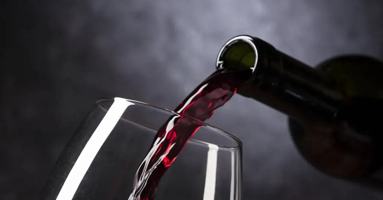 Czerwone wino leje się z butelki do kieliszka. Mrożenie wina w zamrażarce do celów kulinarnych może zmienić jego konsystencję.