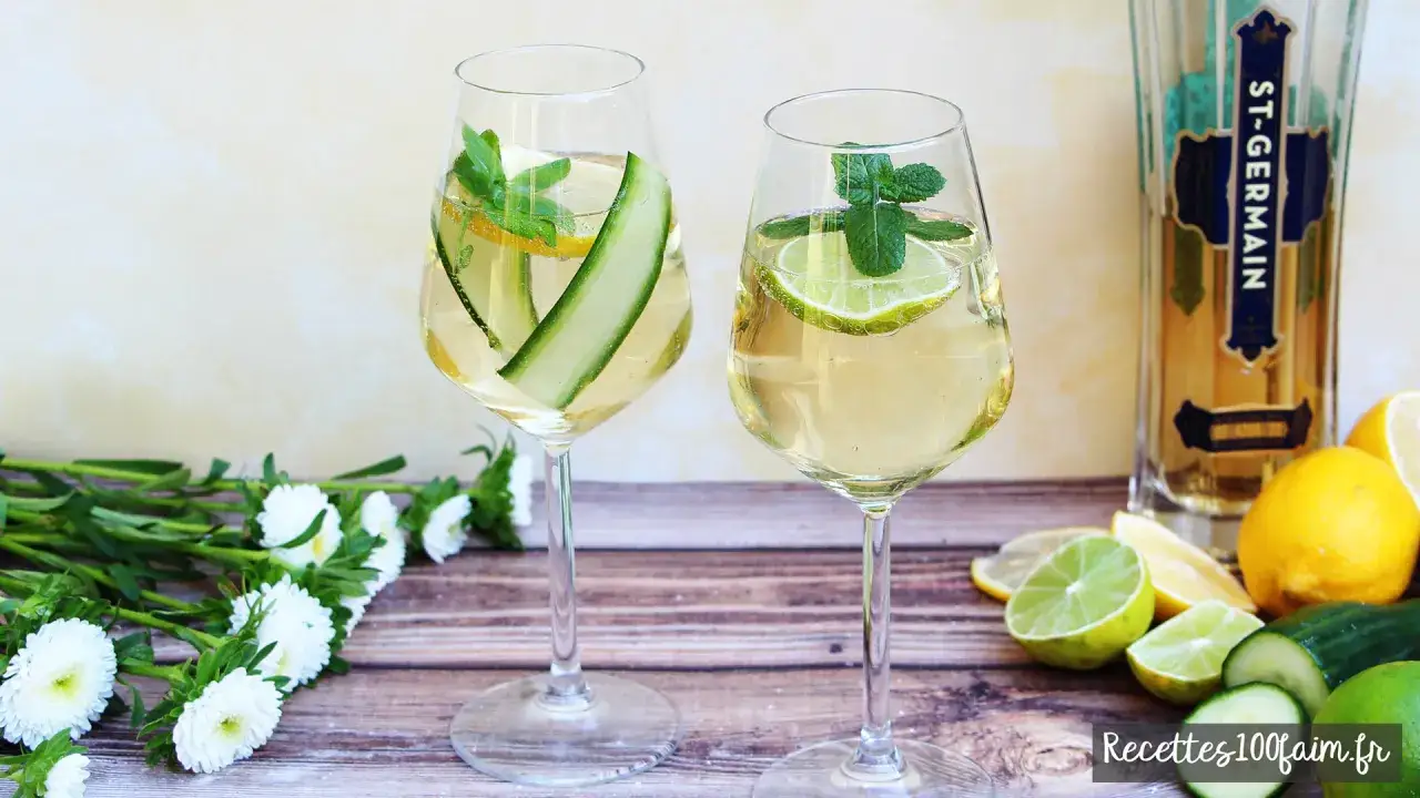 Deux verres de spritz Saint Germain, garni de concombre, citron et menthe, &agrave; c&ocirc;t&eacute; d'une bouteille de liqueur et de fruits frais.