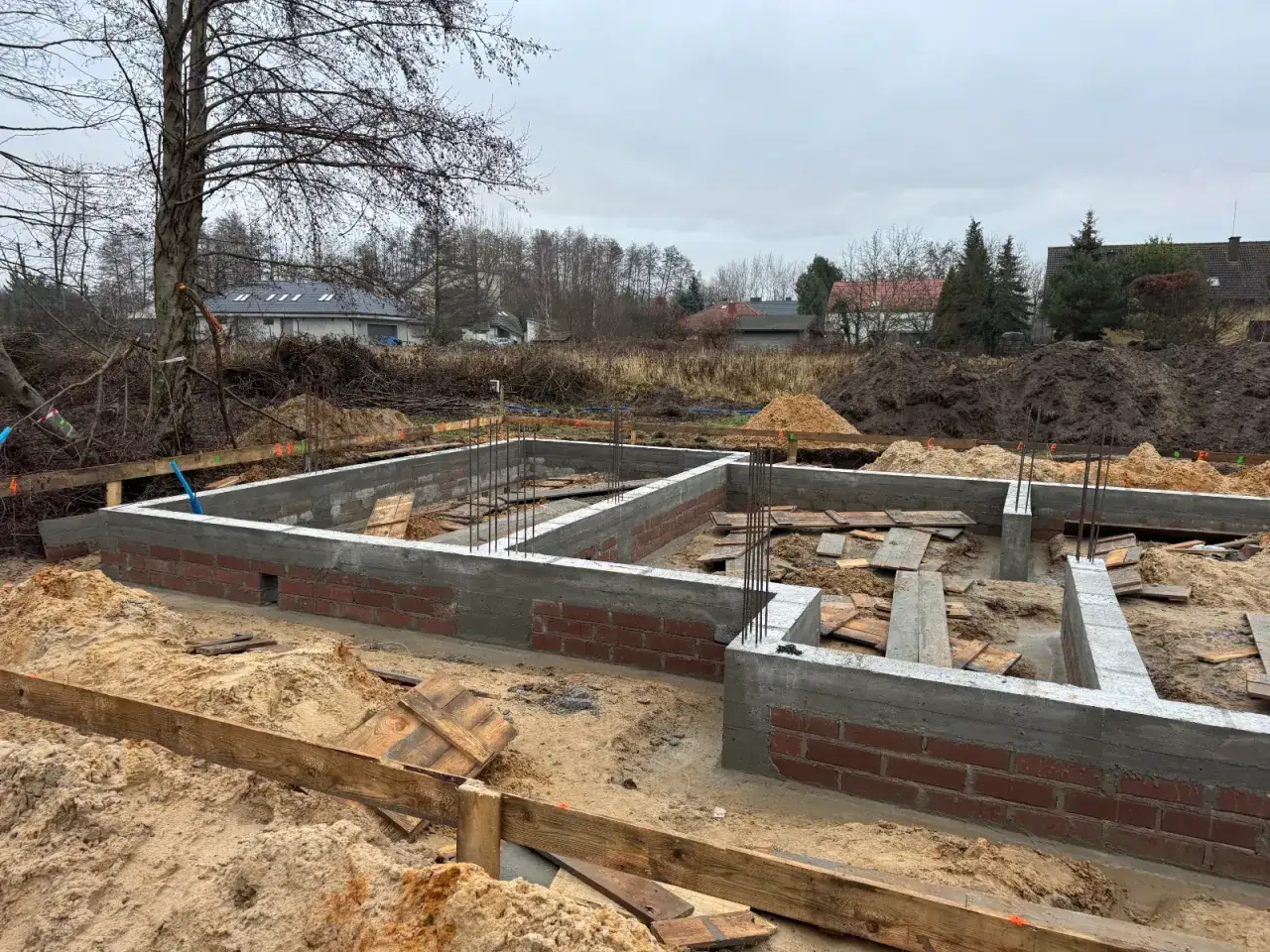Fundament domu w budowie. Widoczna zbrojona ława fundamentowa i ściany z pustaków szalunkowych. To pierwszy etap budowy domu krok po kroku.