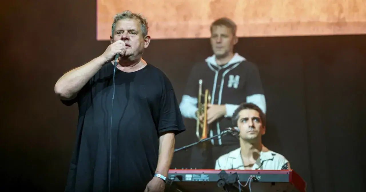 Kazik Staszewski śpiewa, a za nim trębacz i klawiszowiec. To scena z koncertu, gdzie wybrzmiewają jego kultowe utwory.