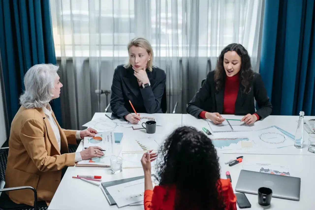 Four business professionals analyze charts and graphs, discussing strategies for their performance management system.