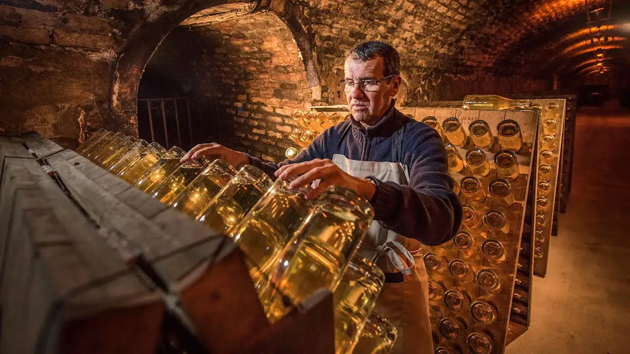 Man i k&auml;llare med flaskor, kanske en del av processen f&ouml;r att skapa en exklusiv champagne som Jaques Selosse.