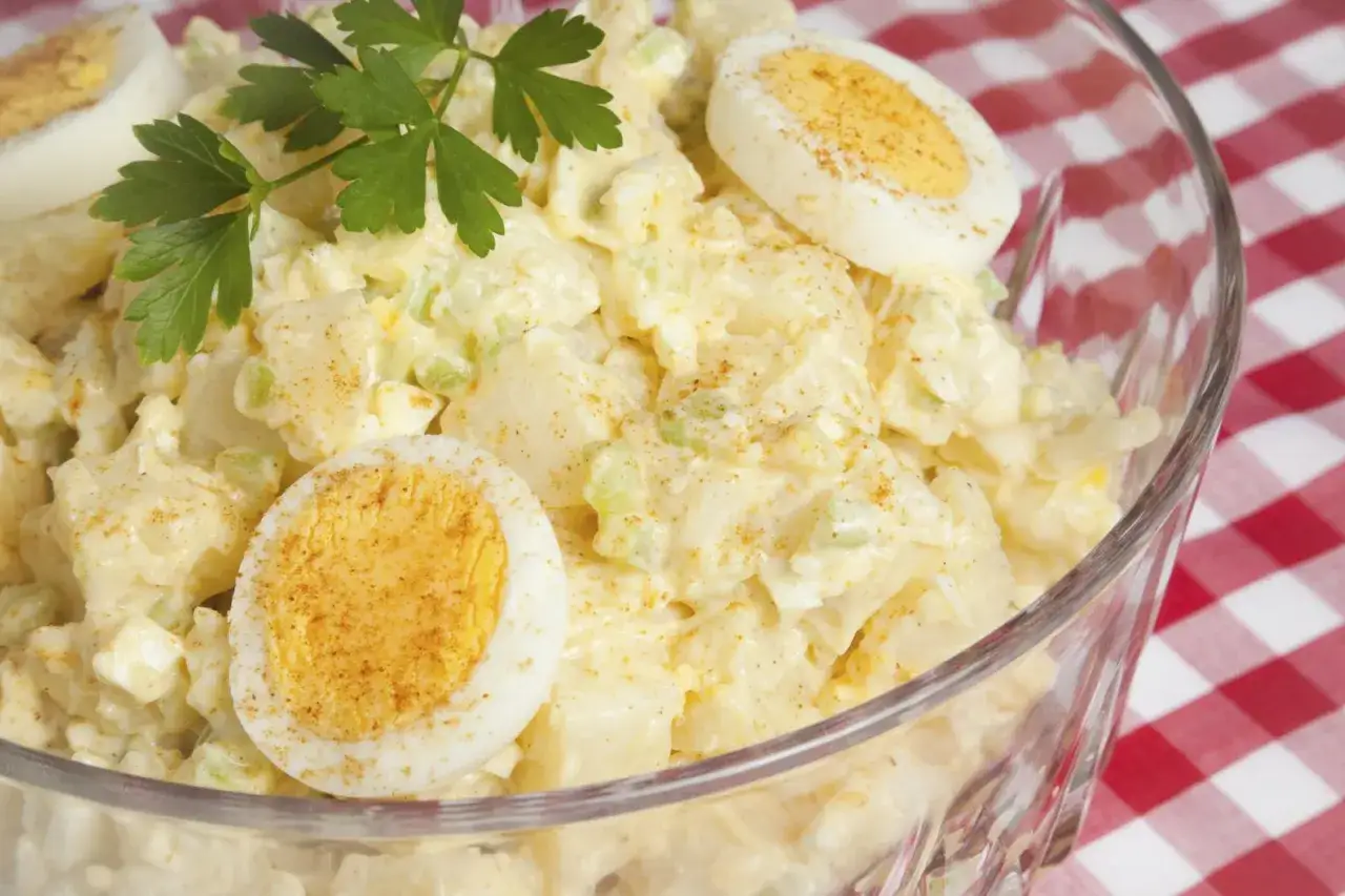 Deliciosa ensalada de patata cremosa con trozos de huevo duro y perejil fresco, espolvoreada con pimentón.
