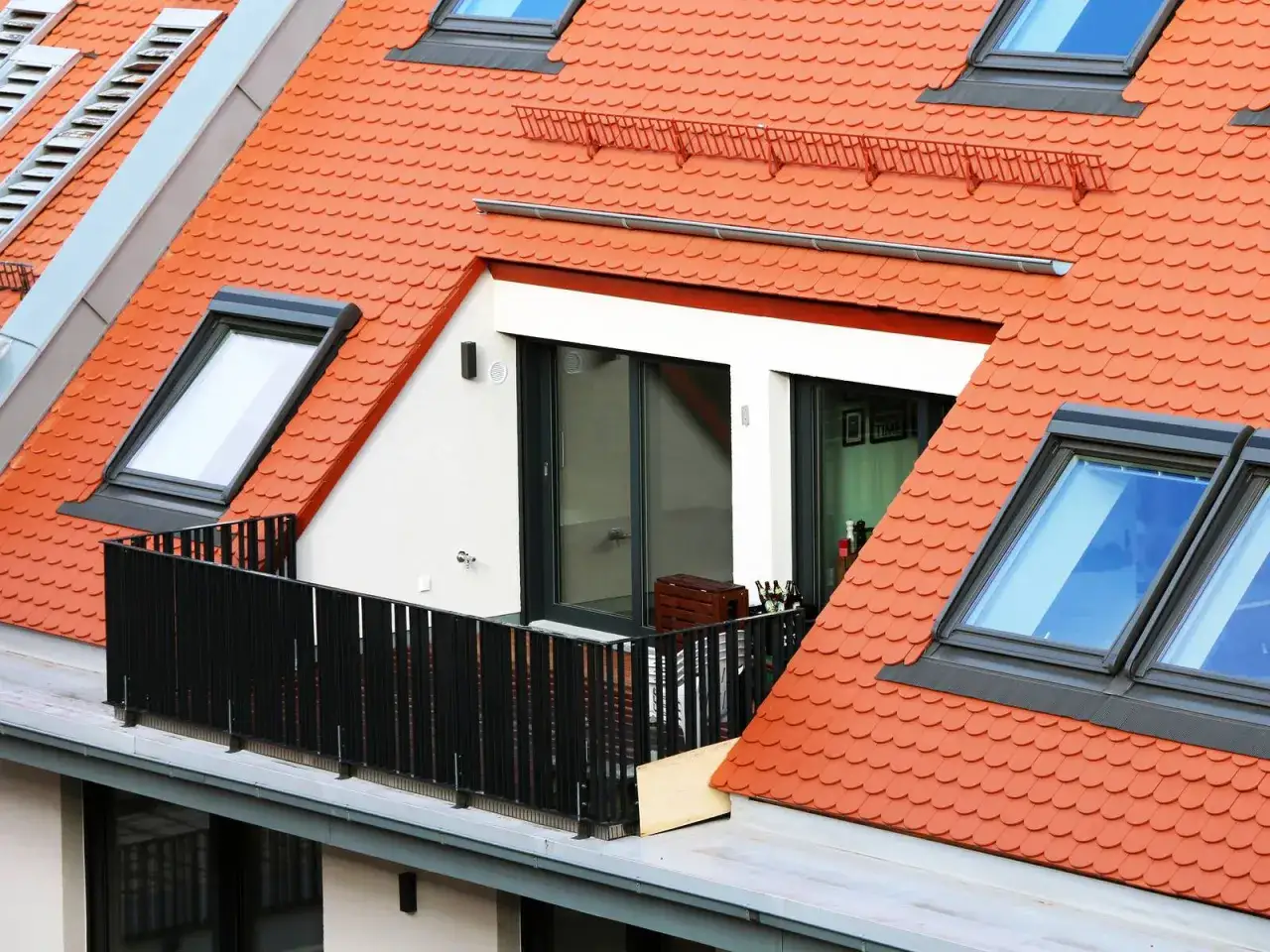 Ein moderner umbauter raum dachgeschoss mit Balkon und Dachfenstern unter roten Ziegeln.
