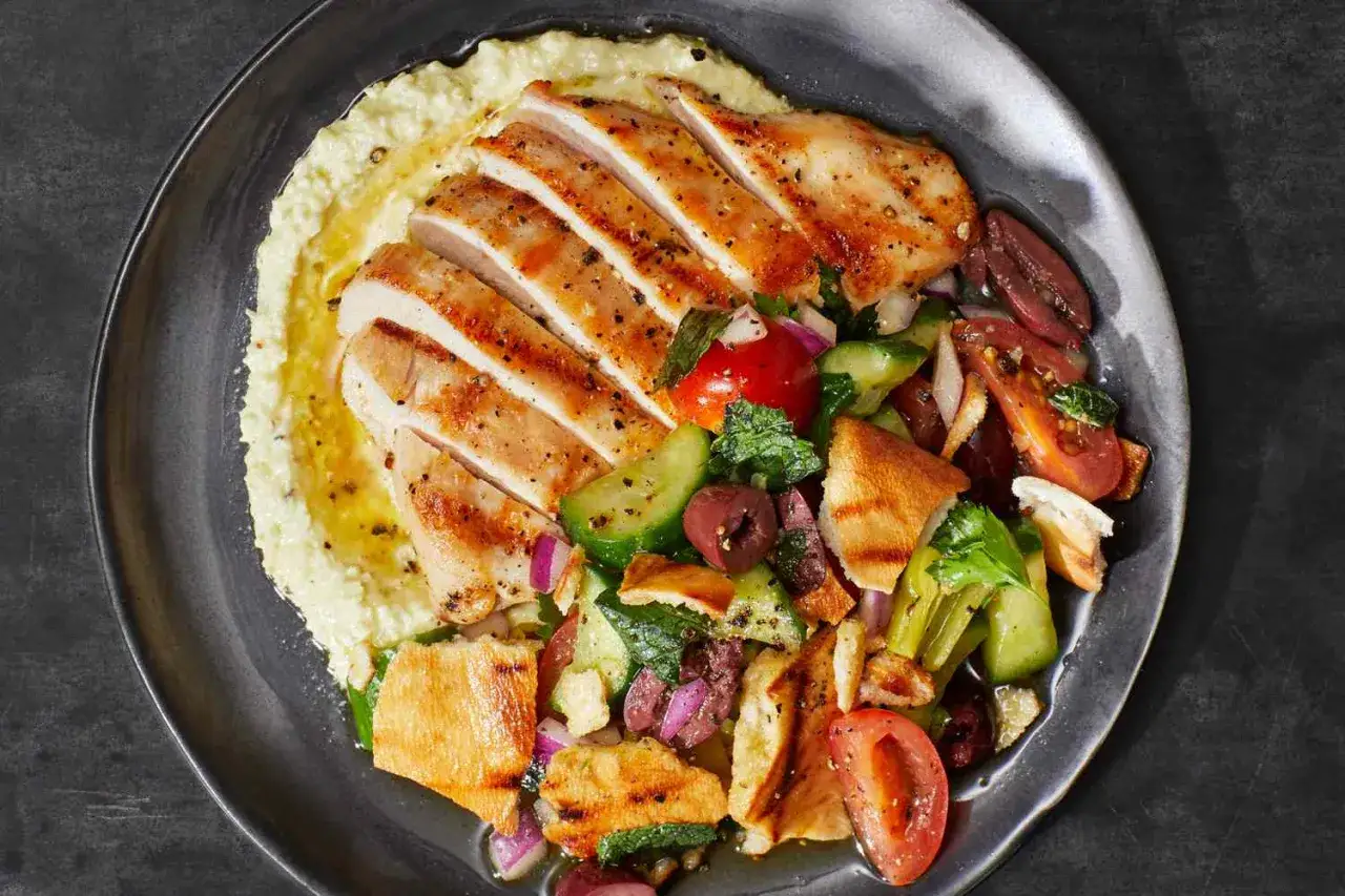 En h&auml;rlig tallrik med grillad kyckling, hummus och en fr&auml;sch sallad med tomat, gurka, oliver och pitabr&ouml;d. Ett perfekt recept med grillad kyckling f&ouml;r en l&auml;tt lunch.