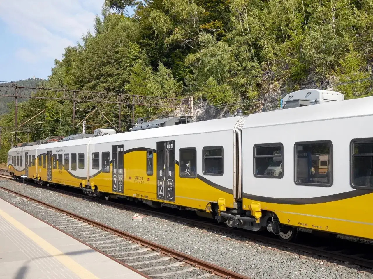 Pociąg PKP w żółto-białych barwach z napisem