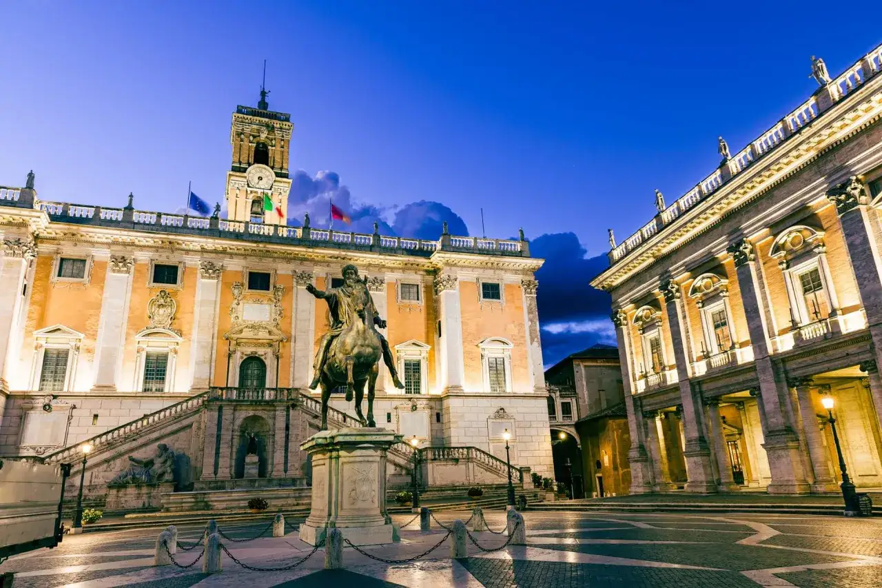 La place du Capitole à Rome, illuminée la nuit, avec la statue équestre de Marc Aurèle devant les musées du Capitole.