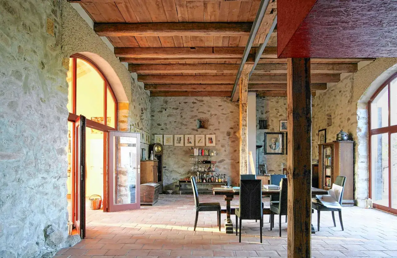 Umbau eines alten Stalls zu Wohnraum mit Genehmigung. Rustikale Steinwände, Holzbalkendecke, Ziegelboden, Essbereich, Bar und Fenster.