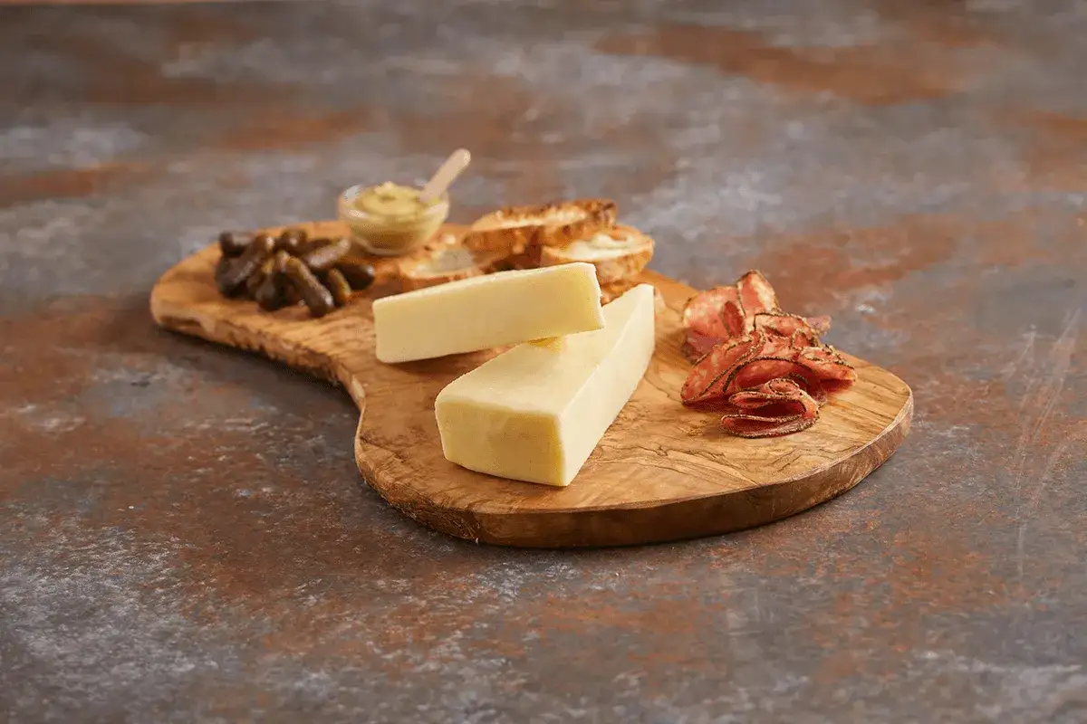 Deska z oliwnego drewna z kawałkami **asiago ser**, piklami, krakersami i plasterkami salami.