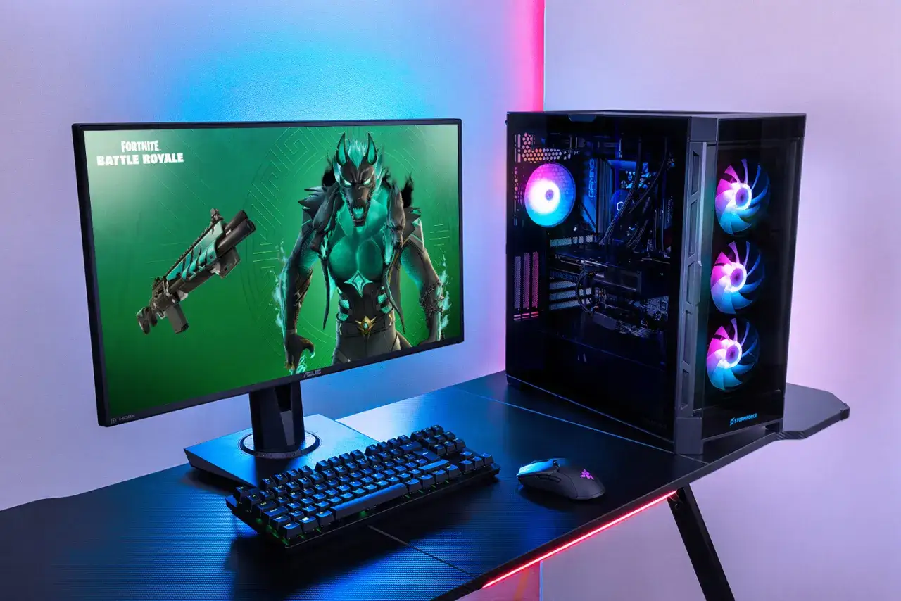 Un PC gamer pr&ecirc;t pour Fortnite, avec un &eacute;cran affichant le jeu, une tour lumineuse et des p&eacute;riph&eacute;riques.