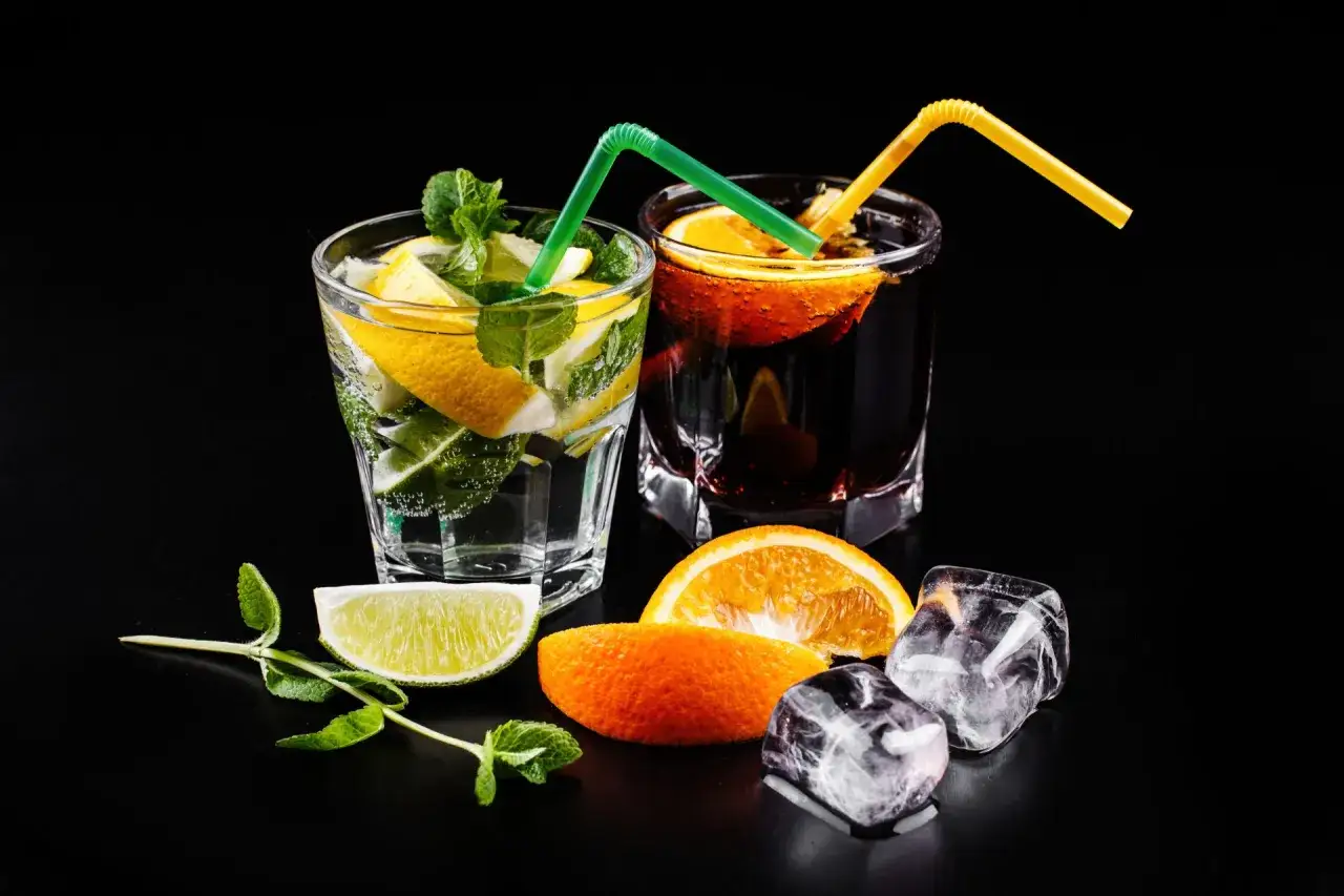 Dwa drinki z cytryną, limonką i miętą oraz pomarańczą. Zastanawiasz się, dlaczego lód w kostkarce domowej szybciej rozwadnia drinka?