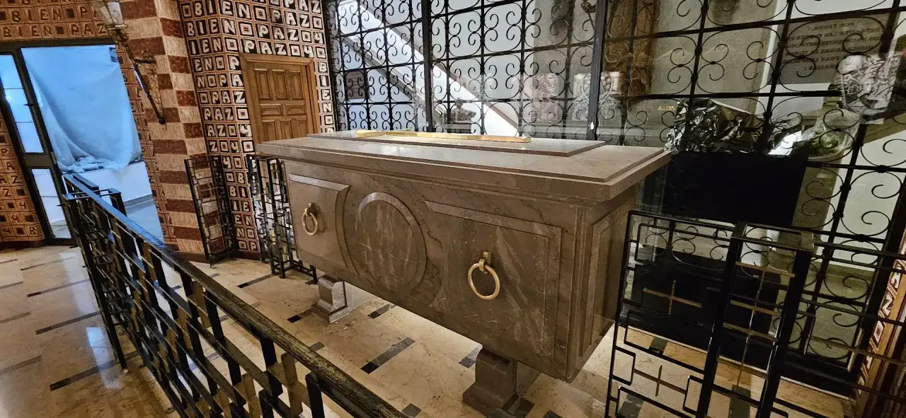 Tumba de mármol con asas doradas, posiblemente la de fray Leopoldo, en un interior con azulejos y rejas ornamentadas.