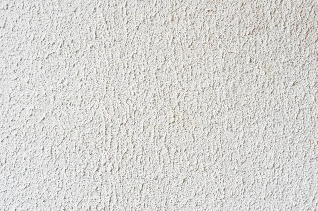 Eine wei&szlig;e Wand mit einer groben Struktur, die zeigt, wie man Rollputz auftragen kann.