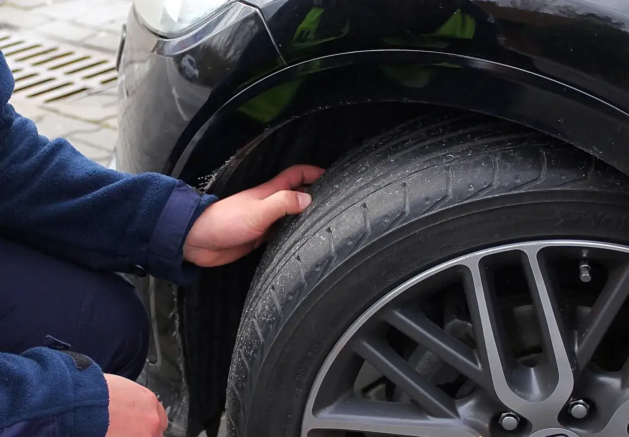 Dłoń sprawdza stan opony, która może być przyczyną drgań kierownicy przy 120 km/h.
