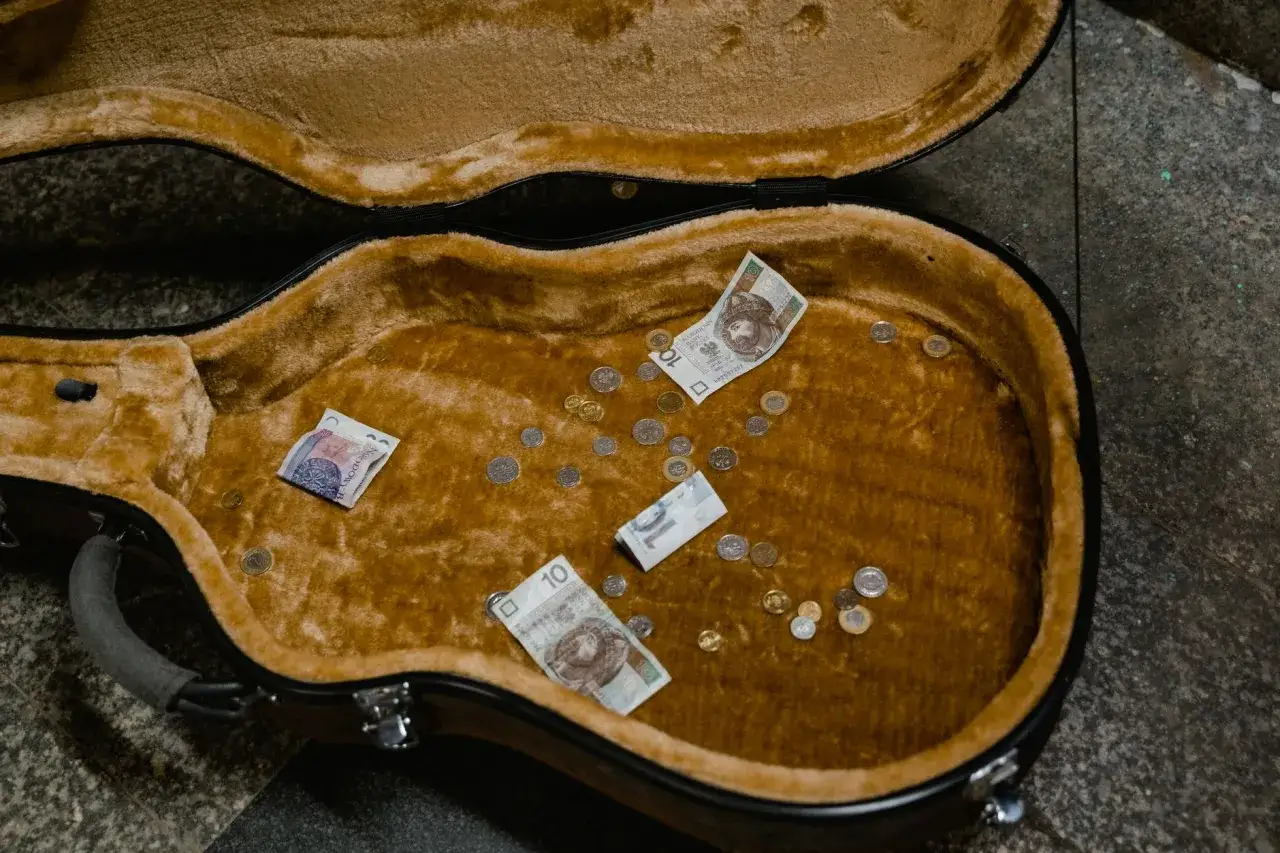 Pusta futerał po gitarze z kilkoma monetami i banknotami 10 zł. Czy to cały guap, jaki udało się zebrać?