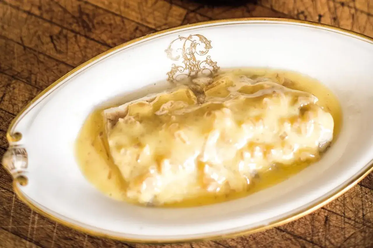 Un délicieux poisson nappé d'une onctueuse sauce beurre blanc, servi dans une assiette élégante.