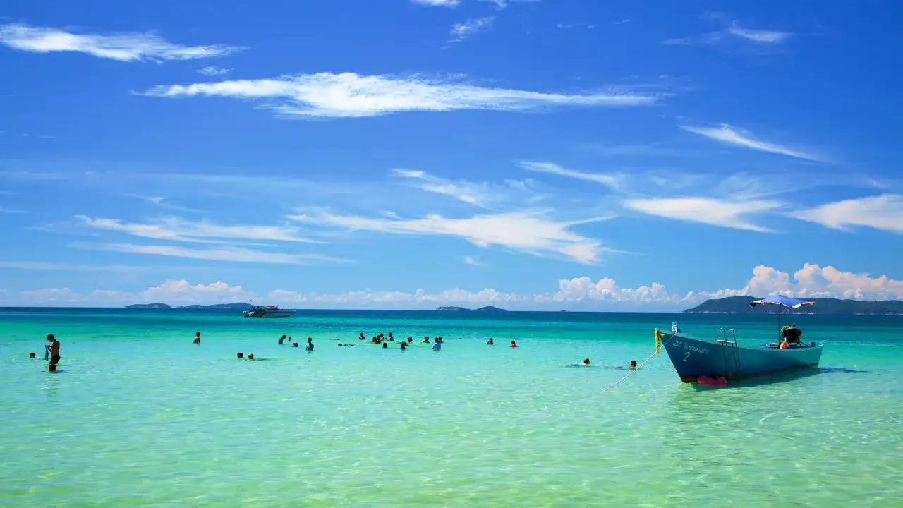 T&uuml;rkisblaues Wasser am pattaya strand. Menschen planschen im Meer, ein Boot liegt vor Anker.
