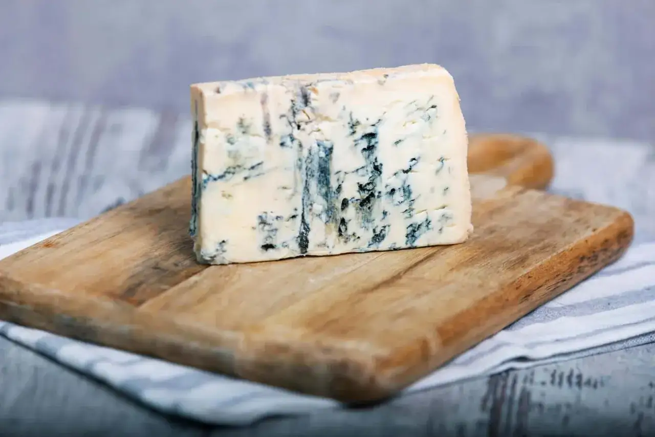 Kawałek kremowego sera z niebieską pleśnią, idealny do deski serów. To wyśmienita gorgonzola dop.
