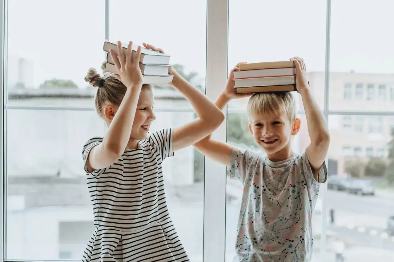 Dzieci z książkami na głowach, symbolizujące radość z nauki i francuski system edukacji.