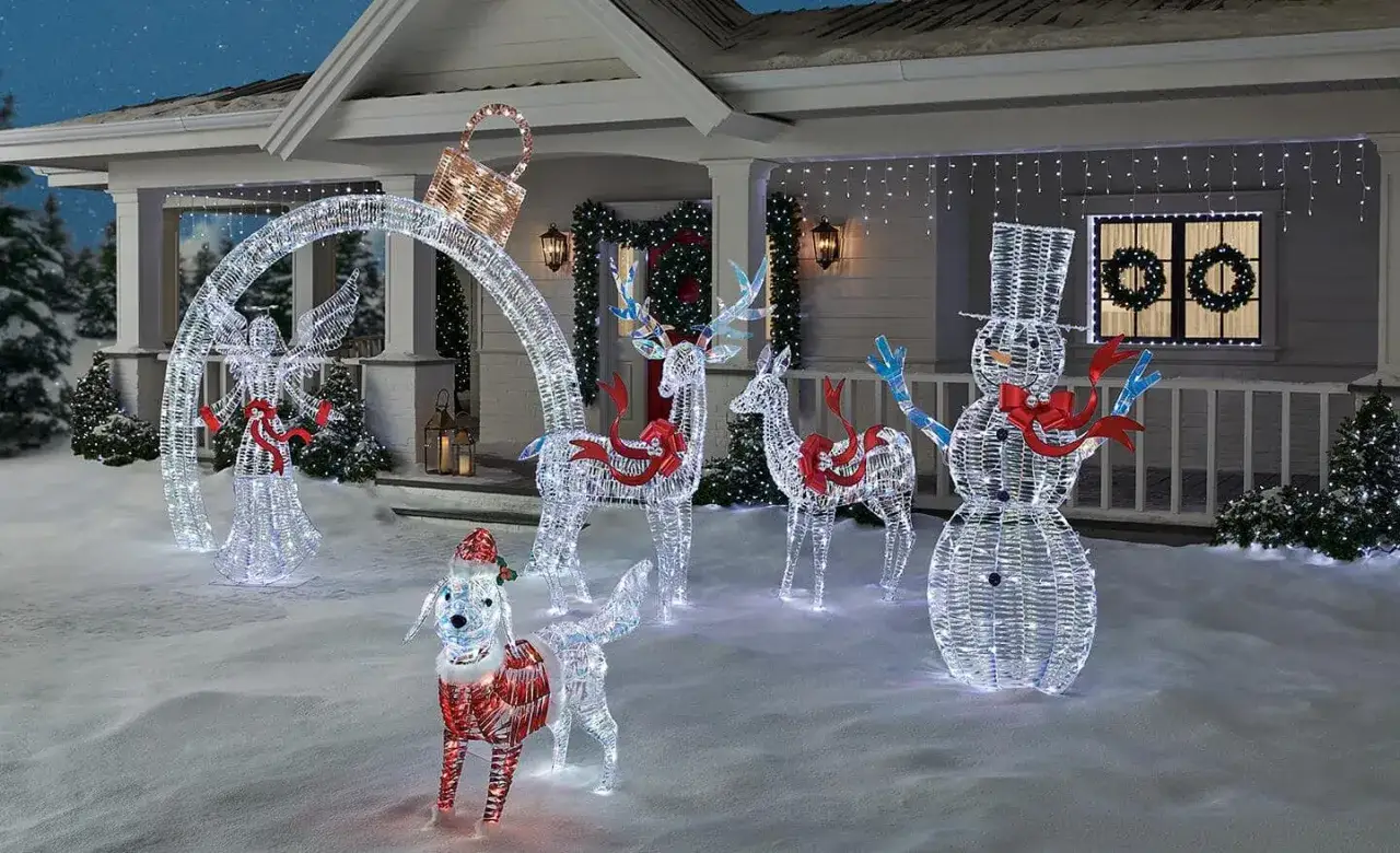 Décoration Noël extérieur à faire soi-même : un ange, un chien, des rennes et un bonhomme de neige lumineux sur un porche enneigé.