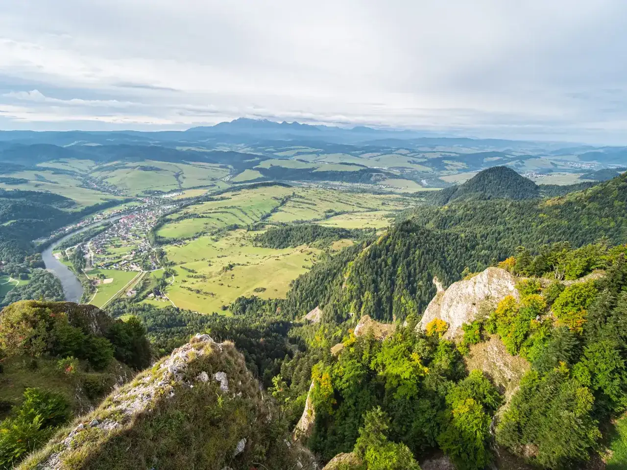 Widok z góry na Pieniny, z rzeką, wsią i zielonymi wzgórzami. To piękne pieniny atrakcje, które warto zobaczyć.